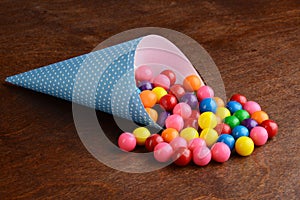 Colorful bubble gumballs in a blue paper cone