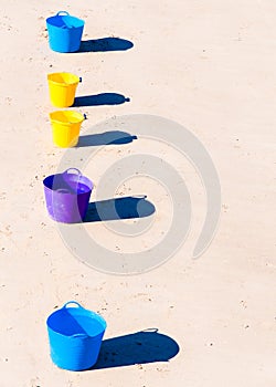 Colorful buckets on the beach sand