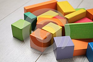 Colorful building blocks on wooden floor, closeup