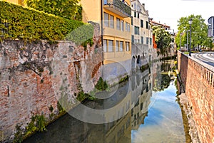 Colorful buildings, architecture, water reflections on city canal and old facade with blue sky in Padua Veneto, italy