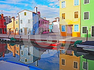 Colorful buildings reflect in the canal on the island of Burano in Italy.