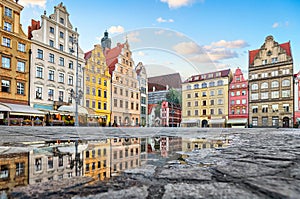 Colorful buildings reflecting in a puddle on Rynek square in Wroclaw