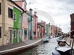 Colorful buildings of Venice on the bay of a canal with boats on a cloudy day in Italy