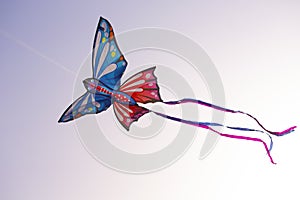 Colorful butterfly kite with bright ribbons is flying in the sky