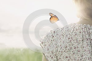 A colorful butterfly leans delicately on the shoulders of a girl