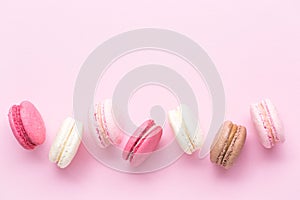 Colorful cake macaron or macaroon isolated over pastel pink background. Top view