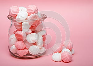 Colorful candies in jar on table on pink background