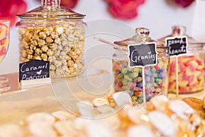 Colorful Candies in jars on a dessert table with donuts, cookies
