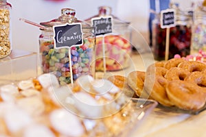 Colorful Candies in jars on a dessert table with donuts, cookies