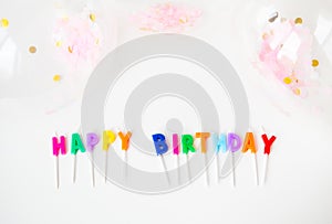 Colorful candles with the inscription Happy Birthday isolated on a white background along with confetti. Holiday and