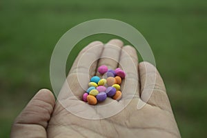 Colorful candy in hand on green grass