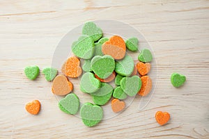 Colorful candy hearts orange and green on wooden background Top