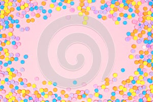 Colorful candy sprinkles frame on a pink background