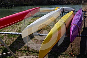 colorful canoes lie on the river bank. close-up view from the top side
