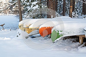 Colorful canoes lying covered in snow in winter