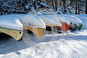 Colorful canoes lying covered in snow in winter