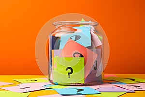 Colorful cards with question marks in glass jar on background