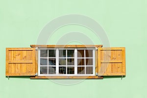 Colorful Caribbean Window and Shutters in a Green Wall