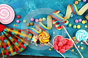 Colorful carnival border over a cool textured background with copy space with party hats, candy, streamers and hearts. Party
