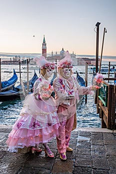 Colorful carnival masks at a traditional festival in Venice against gondolas, Italy