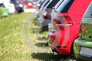 Colorful cars parked on the grass. Red and green automobiles