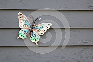 A colorful ceramic butterfly on the outside wall of a home