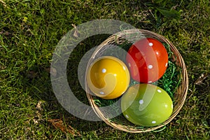 Colorful ceramic easter eggs in a basket on a meadow