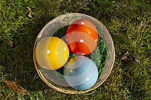 Colorful ceramic easter eggs in a basket on a meadow