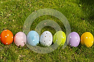 Colorful ceramic easter eggs in a basket on a meadow