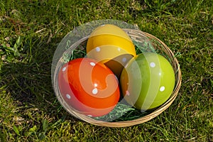 Colorful ceramic easter eggs in a basket on a meadow