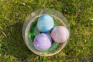 Colorful ceramic easter eggs in a basket on a meadow
