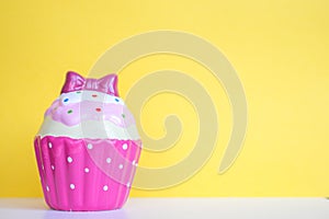 Colorful ceramic muffin on yellow background. Free space for text. Holiday concept. Selected focus