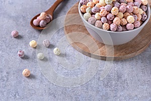 Colorful cereal corn balls mix sweets in a bowl on gray cement background