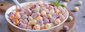 Colorful cereal corn balls mix sweets in a bowl on gray cement background