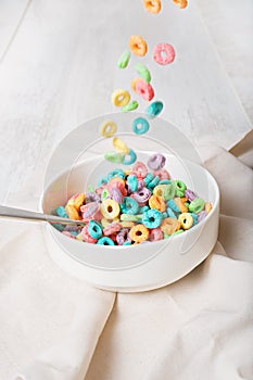 Colorful cereal falling on a bowl on a white background