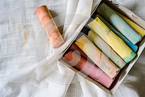 colorful chalks in a box over white fabric background