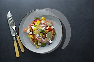 Colorful cherry tomatoes and basil salad in a plate, dark background. Healthy, summer food