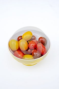 Colorful cherry tomatoes in a jellow bowl.
