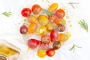 Colorful cherry tomatoes red, garnet and yellow, fresh and raw. With drops of water and rosemary. Homemade and rustic look with