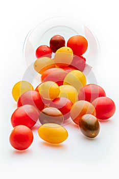 Colorful cherry tomatoes red, garnet and yellow, fresh and raw. In plastic jar. Isolated.