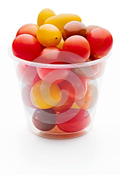 Colorful cherry tomatoes red, garnet and yellow, fresh and raw. In plastic jar. Isolated on white background