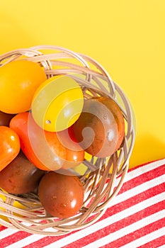 Colorful cherry tomatoes in wicker basket and towel
