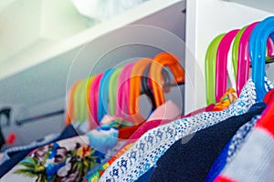 Colorful child hangers with toddler boy shirts hanging in a closet