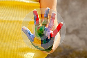 Colorful child`s hand, child showing single colored palm of hand covered in paint to the camera, creativity, arts and crafts