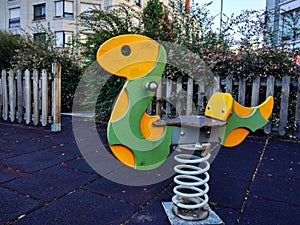 Colorful children playground in public park surrounded by green vegetation with children snake toy close up