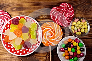 Colorful chocolate candies, lollipops and jelly sweets on wooden table