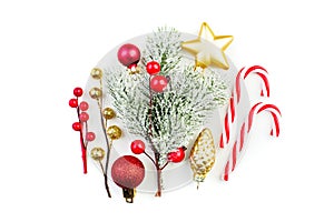 Colorful Christmas decortions. Red baubles, snowy winter holly berries, lollipop and green fir branch on white background