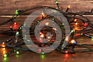 Colorful christmas garland lights on brown wooden background. Christmas Light with Copyspace for New Year Frame or Christmas Layou