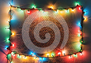 Colorful Christmas lights frame on retro brick wall background