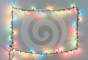 Colorful Christmas lights frame on white wall background